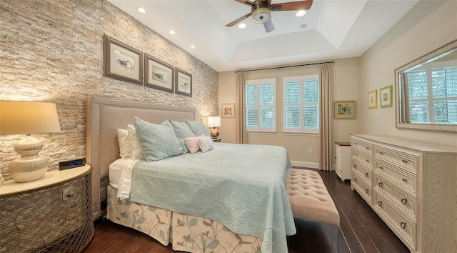 bedroom with ceiling fan, dark hardwood / wood-style flooring, and a raised ceiling