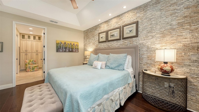 bedroom featuring ceiling fan, dark wood-type flooring, and a tray ceiling