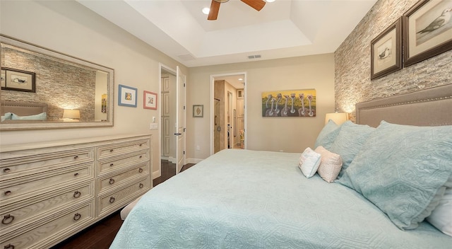 bedroom featuring a raised ceiling, ceiling fan, and dark hardwood / wood-style flooring