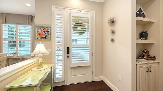 entryway with dark wood-type flooring and built in features