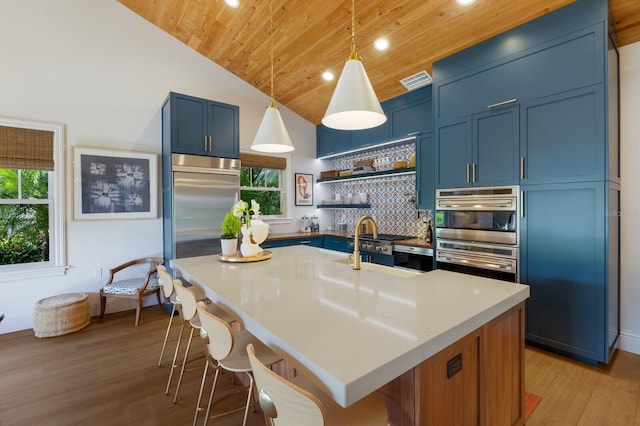 kitchen with a breakfast bar area, wooden ceiling, a kitchen island with sink, blue cabinets, and hanging light fixtures