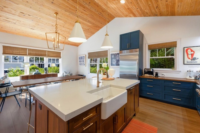 kitchen featuring wood ceiling, stainless steel built in refrigerator, sink, a kitchen island with sink, and blue cabinets