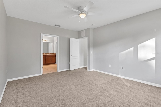 unfurnished bedroom with light colored carpet, ensuite bath, and ceiling fan