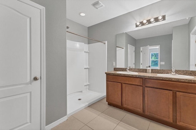 bathroom with a shower, vanity, and tile patterned floors