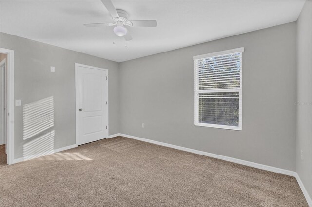 empty room featuring ceiling fan and carpet