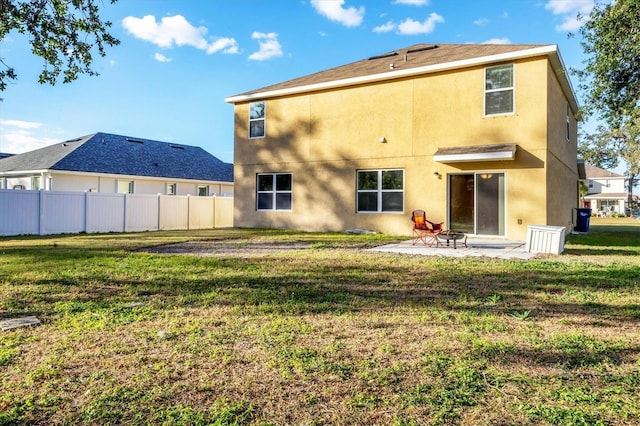 back of property with a yard and a patio