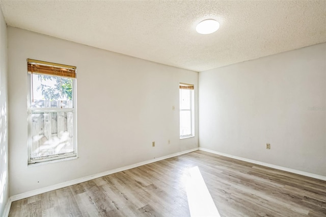 spare room with a textured ceiling and light wood-type flooring