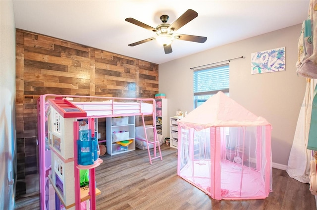 bedroom featuring wood-type flooring, ceiling fan, and wood walls