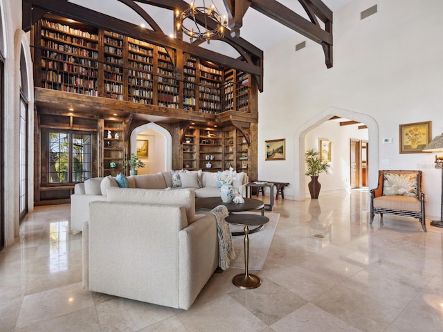 living room featuring a chandelier, a high ceiling, built in shelves, and beam ceiling