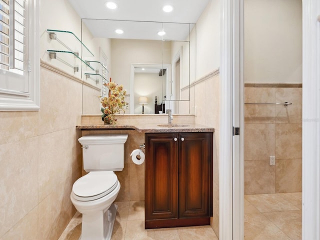 bathroom featuring vanity, toilet, and tile walls