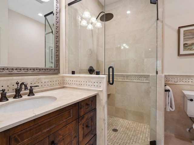 bathroom featuring walk in shower, vanity, toilet, and tile walls