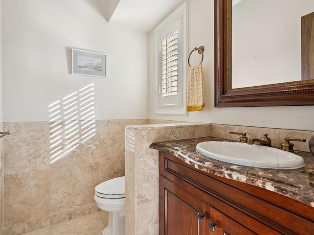 bathroom featuring tile patterned flooring, vanity, toilet, and tile walls