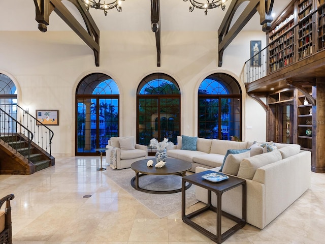 living room with beamed ceiling, a high ceiling, and an inviting chandelier