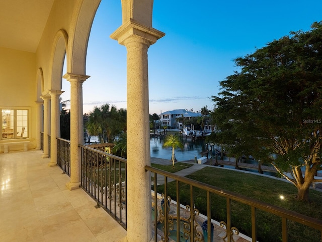 balcony at dusk featuring a water view