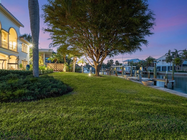 yard at dusk with a boat dock and a water view