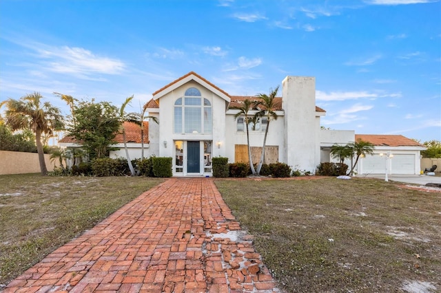 view of front of property with french doors, a garage, and a front lawn