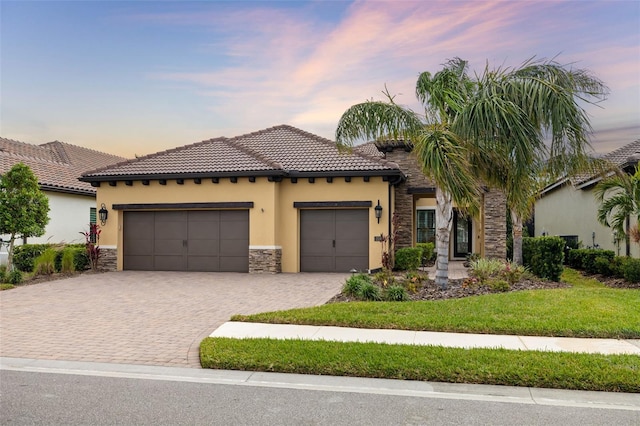 mediterranean / spanish-style house with a garage and a yard