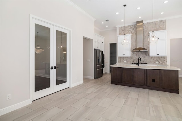 kitchen featuring backsplash, french doors, hanging light fixtures, wall chimney exhaust hood, and stainless steel fridge