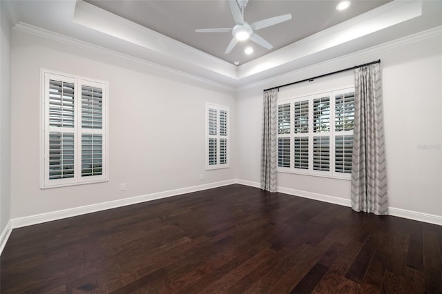 empty room featuring a tray ceiling, ceiling fan, crown molding, and dark hardwood / wood-style floors