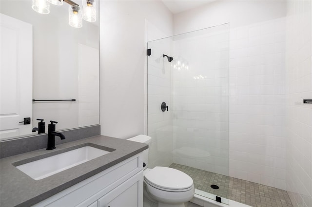 bathroom with a tile shower, vanity, and toilet