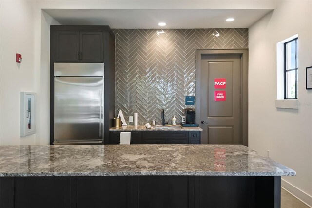 kitchen with light stone countertops and stainless steel built in refrigerator