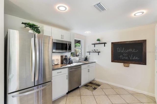 kitchen with decorative backsplash, sink, light tile patterned floors, stainless steel appliances, and white cabinets