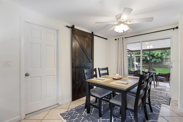 tiled dining space featuring ceiling fan and a barn door