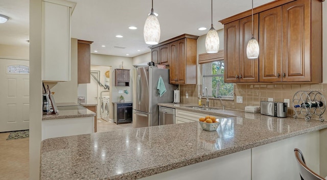 kitchen with decorative light fixtures, light stone counters, sink, and appliances with stainless steel finishes