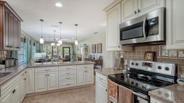 kitchen featuring kitchen peninsula, appliances with stainless steel finishes, backsplash, light tile patterned floors, and decorative light fixtures