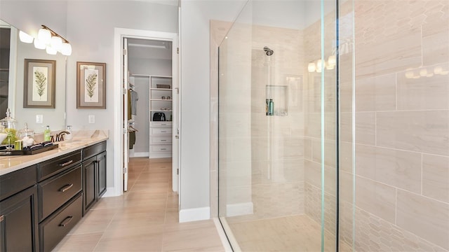 full bath with double vanity, a sink, tile patterned flooring, a shower stall, and a walk in closet