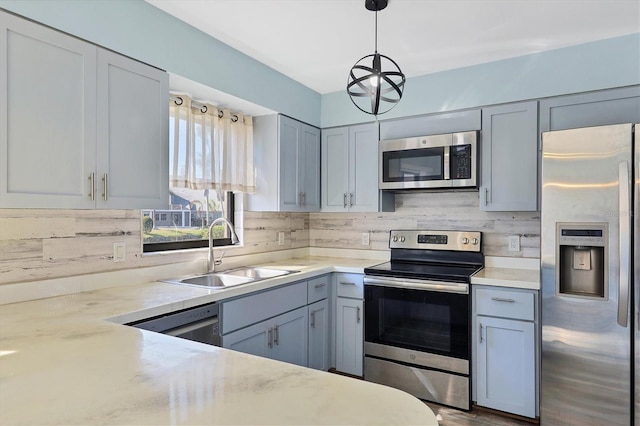 kitchen featuring appliances with stainless steel finishes, sink, light stone counters, pendant lighting, and tasteful backsplash