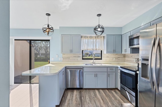 kitchen with hanging light fixtures, appliances with stainless steel finishes, sink, and kitchen peninsula