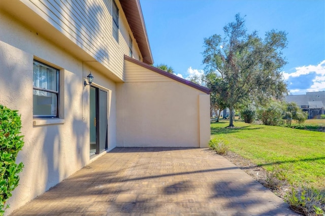 view of property exterior featuring a patio and a lawn