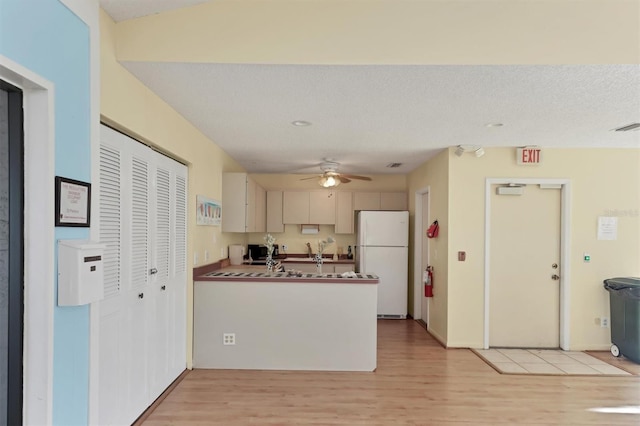 kitchen with a textured ceiling, white refrigerator, ceiling fan, and light hardwood / wood-style flooring