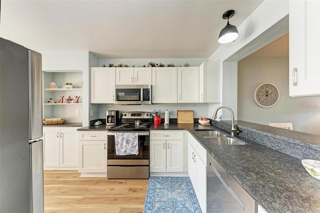 kitchen featuring stainless steel appliances, sink, pendant lighting, light hardwood / wood-style flooring, and white cabinetry