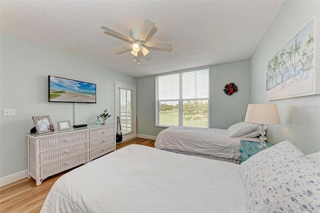 bedroom with a textured ceiling, light hardwood / wood-style floors, and ceiling fan