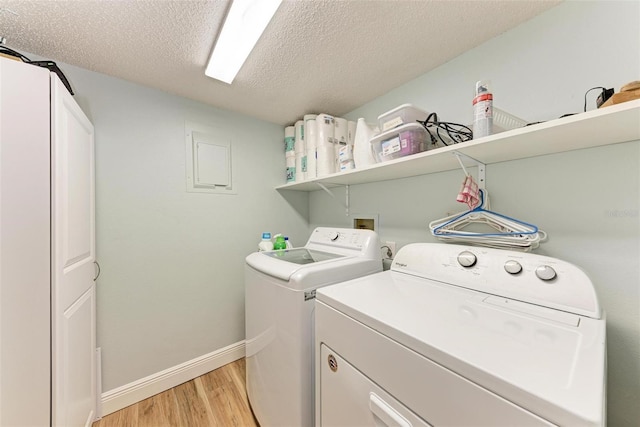 laundry room with independent washer and dryer, a textured ceiling, and light hardwood / wood-style floors