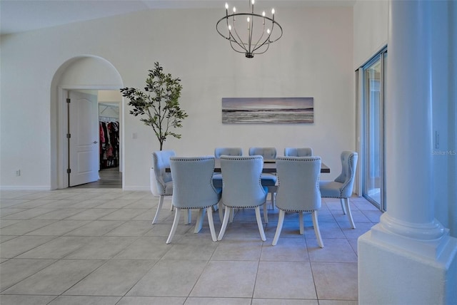 tiled dining space featuring lofted ceiling, an inviting chandelier, and ornate columns