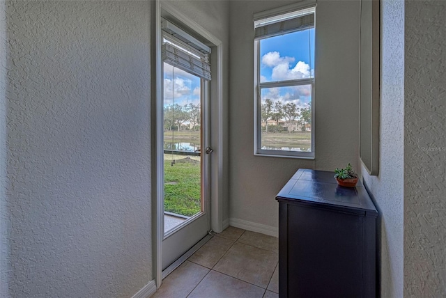 entryway featuring a water view and light tile patterned flooring