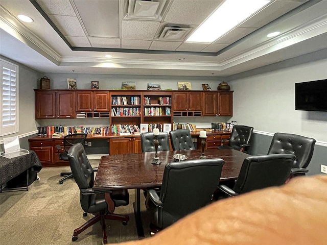 carpeted office with ornamental molding and a tray ceiling