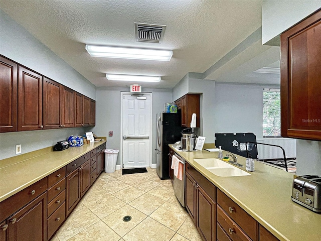 kitchen with a textured ceiling, appliances with stainless steel finishes, light tile patterned floors, and sink