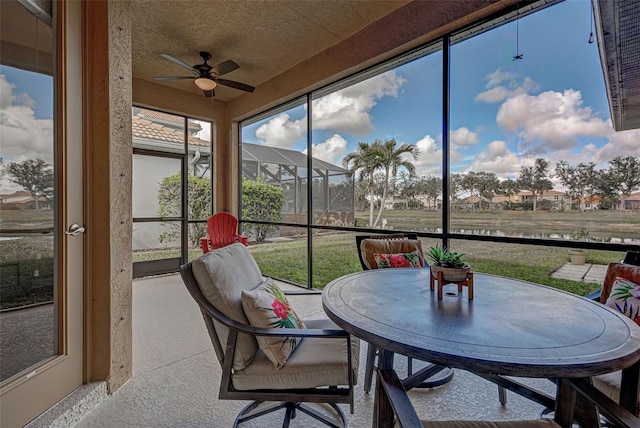 sunroom with ceiling fan and a water view