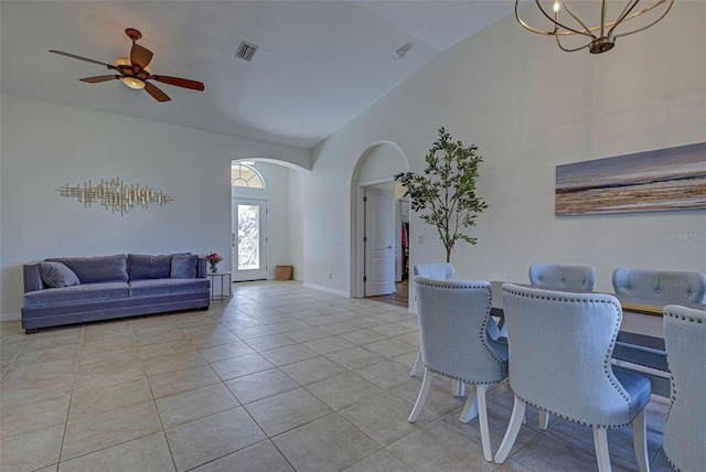 tiled dining area featuring ceiling fan with notable chandelier and vaulted ceiling