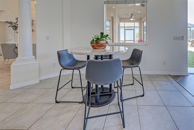 tiled dining space with ceiling fan and ornate columns