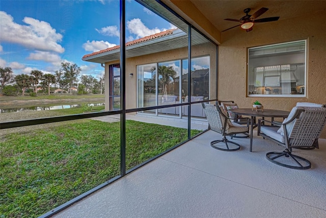 sunroom / solarium with ceiling fan and a water view