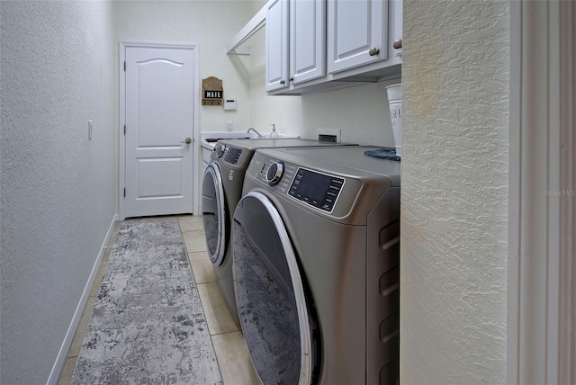 clothes washing area featuring separate washer and dryer, cabinets, and light tile patterned floors