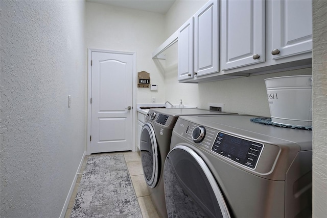 laundry area featuring light tile patterned floors, separate washer and dryer, and cabinets