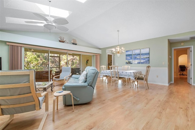 dining space with ceiling fan with notable chandelier, vaulted ceiling, and light wood-type flooring