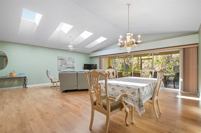 dining area with vaulted ceiling with skylight, ceiling fan with notable chandelier, and light wood-type flooring