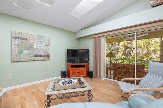 living room featuring lofted ceiling with skylight, hardwood / wood-style floors, and ceiling fan